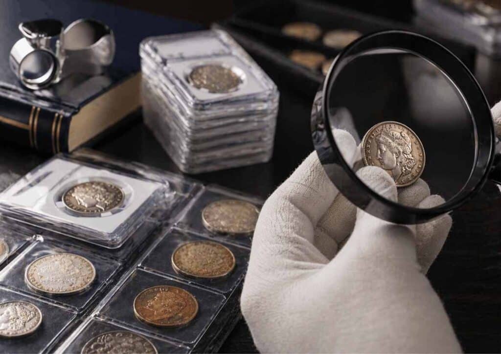Expert examining rare coins with magnifying glass for grading process, showcasing professional coin authentication by a trusted Sacramento gold buyer.